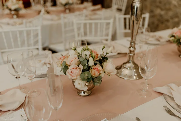 A blush rose centerpiece in a silver candlestick holder.