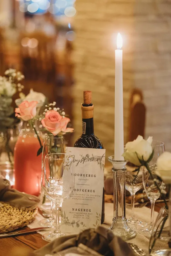 A candlelit table setting with a menu card and roses.