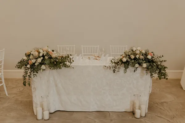 A Mr and Mrs sweetheart table styled with a blush and white floral garland.