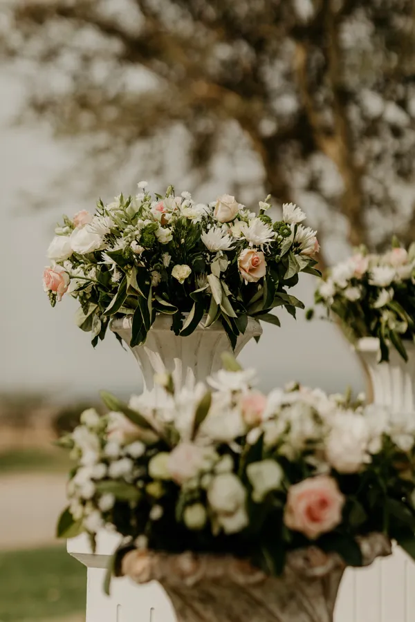 An outdoor ceremony urn arrangement with pink and white roses.