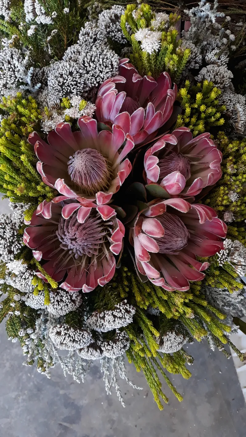 An overhead view of a pink protea and fynbos bouquet.