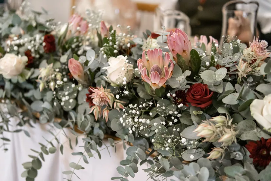 A pink protea and red rose table runner arrangement.