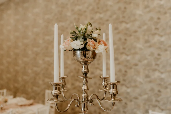 A silver candelabra with blush roses and taper candles.