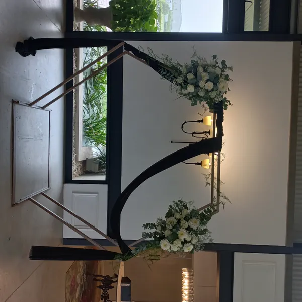 A wedding arch decorated with white roses and a black drape.