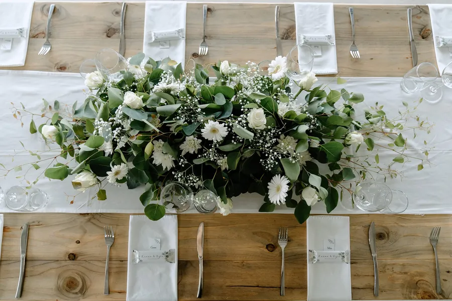 A white rose, gerbera, and eucalyptus centerpiece arrangement.